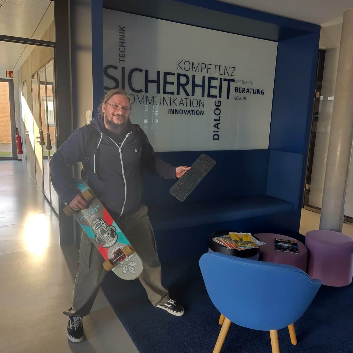 Roland Golla mit Skateboard und Funktastatur vor Wortwolke zu IT-Sicherheit